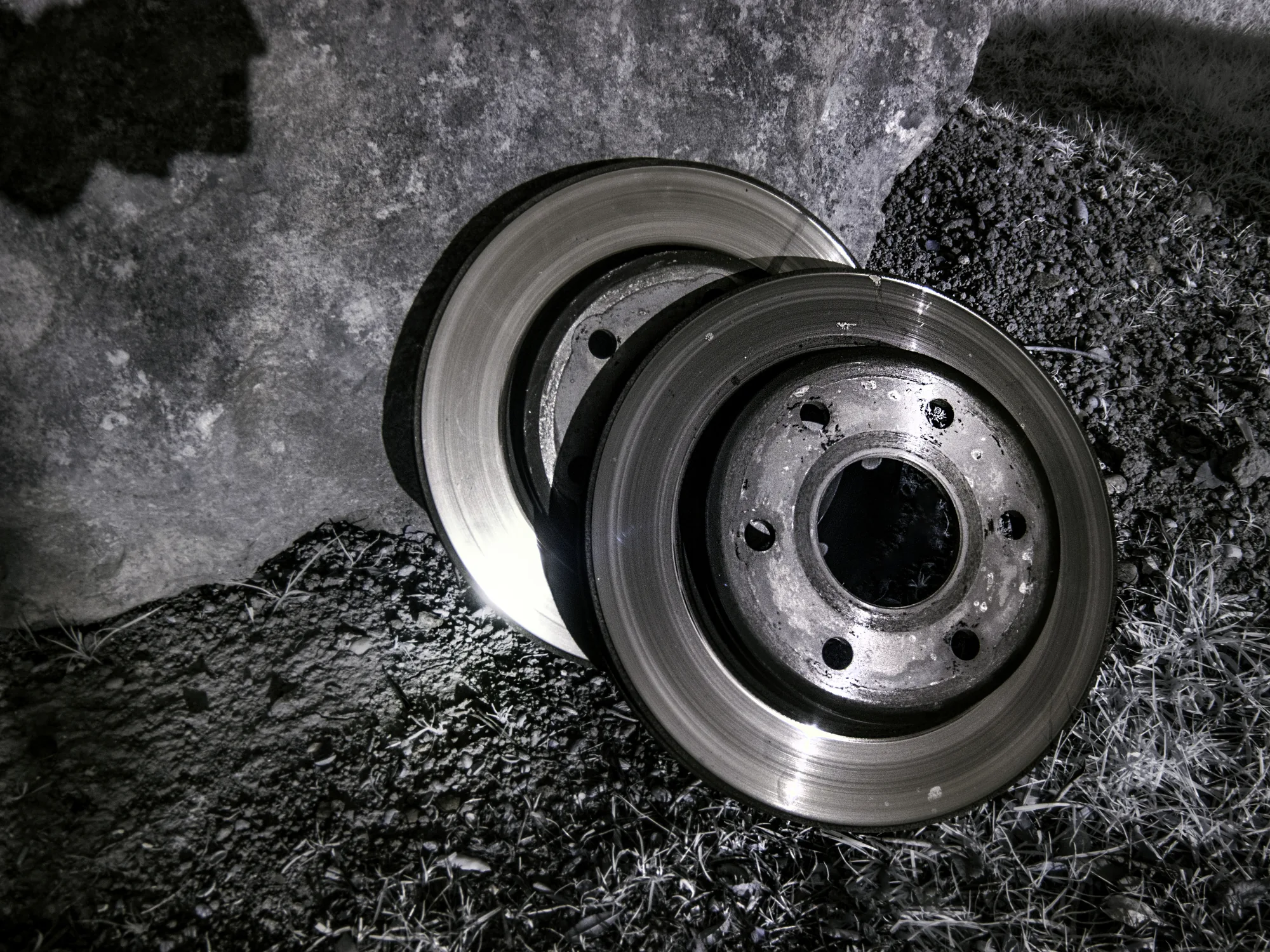 Two automotive brake discs photographed on a textured surface
