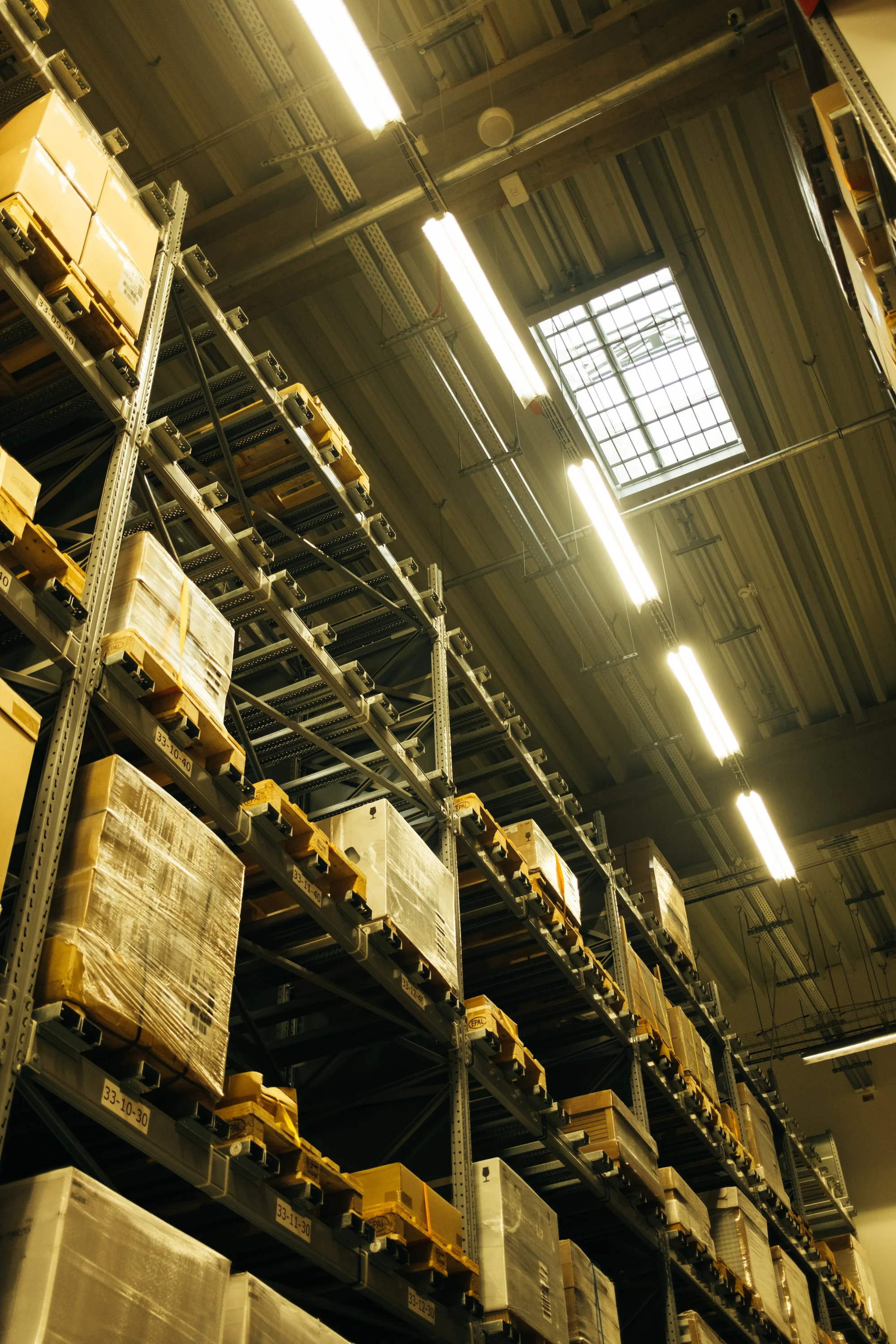 Tall pallet racks holding wrapped boxes inside a warehouse